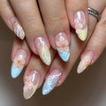 Hand with pastel blue and yellow seashell press-on nails featuring 3D floral designs