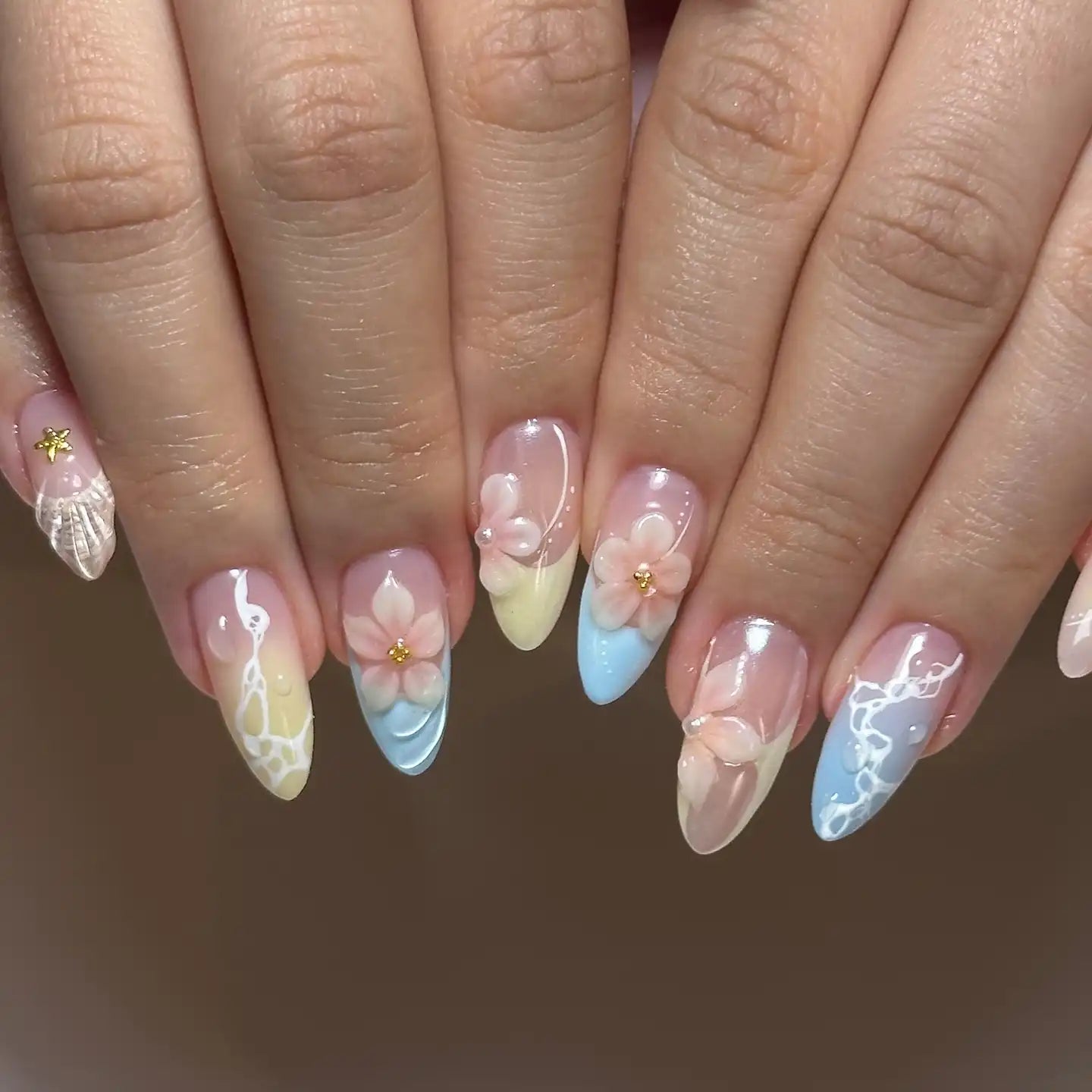Handmade press-on nails with pastel ombre, 3D pink blossom flowers, and seashell accents.