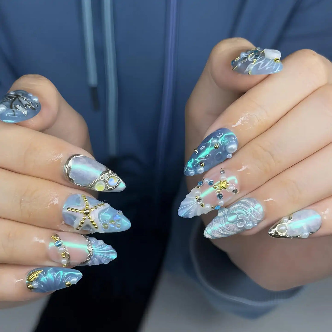 Handmade blue press-on nails with starfish, seashell, and pearl ocean-themed 3D designs.
