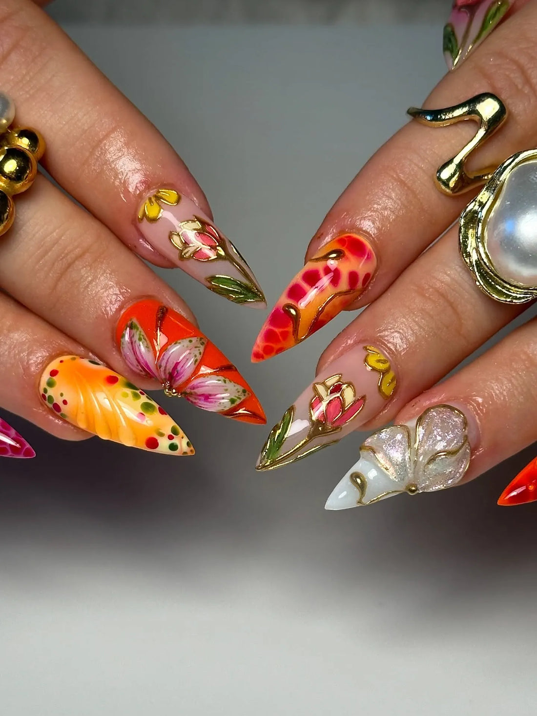 Handmade press-on nails with bold red, orange, and gold 3D floral and butterfly designs.