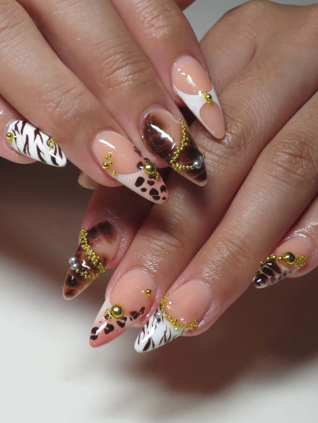 Handmade press-on nails with brown leopard and zebra print French tips, gold bead accents.