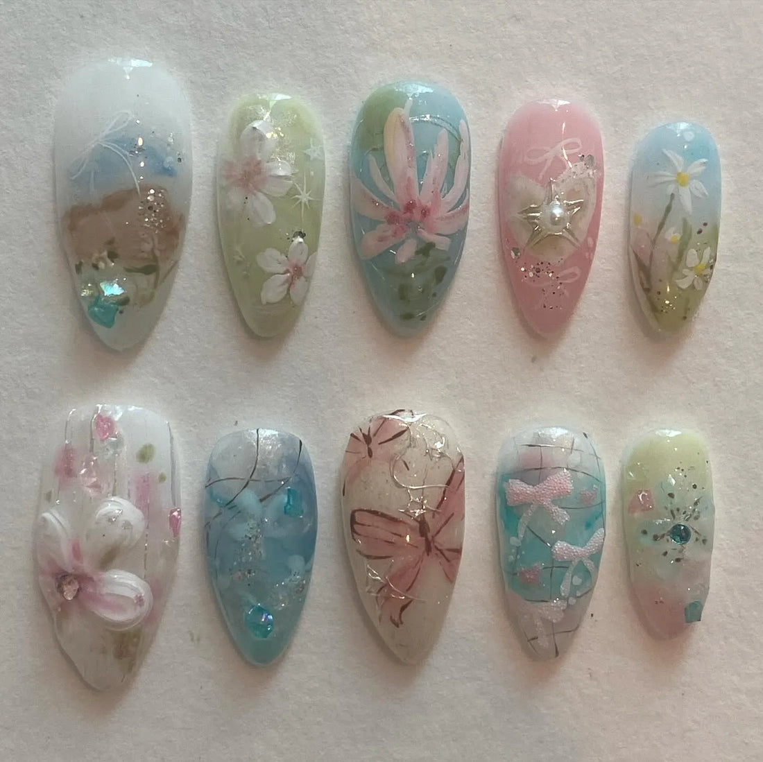 Handmade press-on nails with pastel butterfly, floral, and nature-inspired spring designs