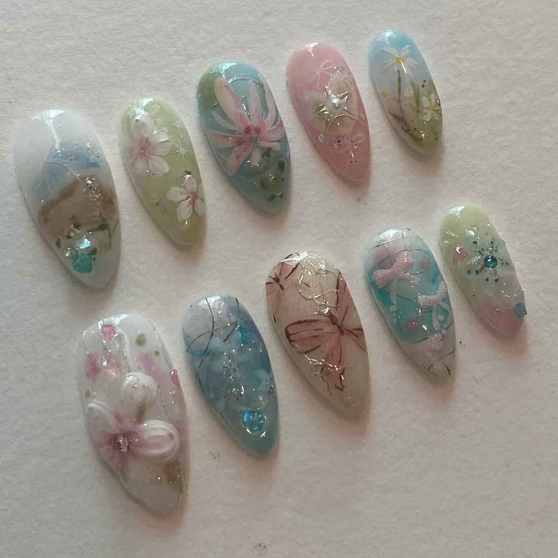 Handmade press-on nails with pastel butterfly, floral, and nature-inspired spring designs