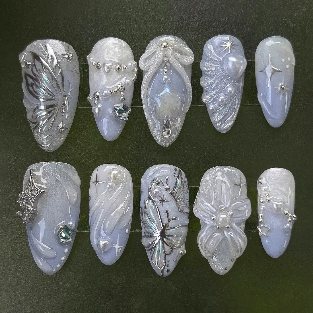 Handmade press-on nails with pearl, butterfly, moon, and star designs on iridescent base