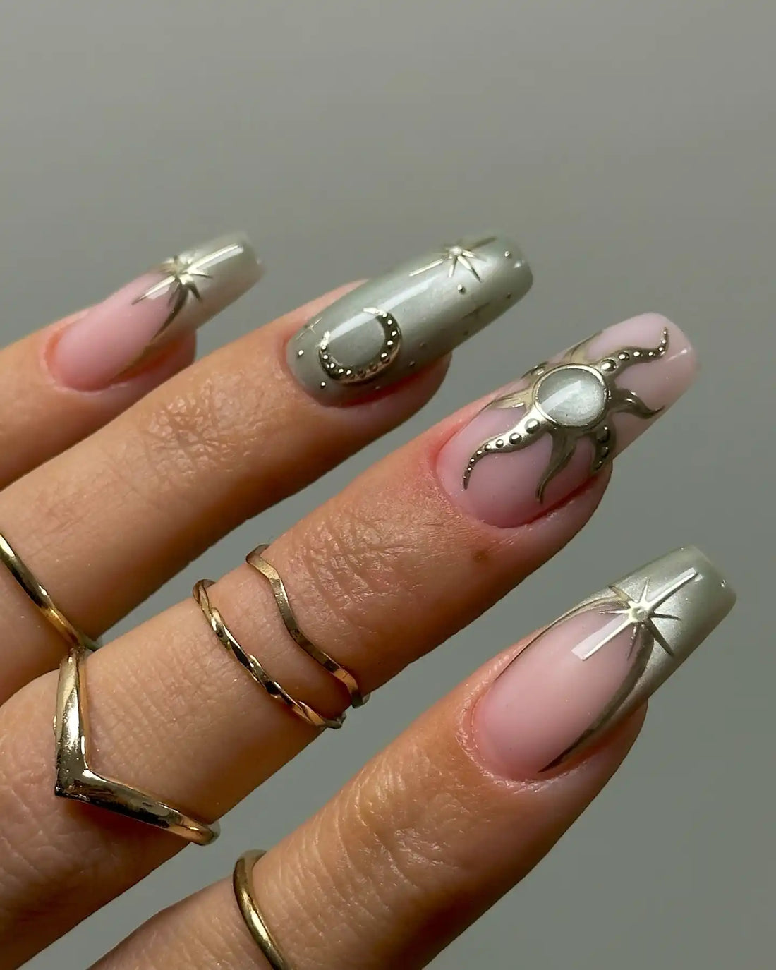 Hand holding celestial green press-on nails with gold star, moon, and sun designs