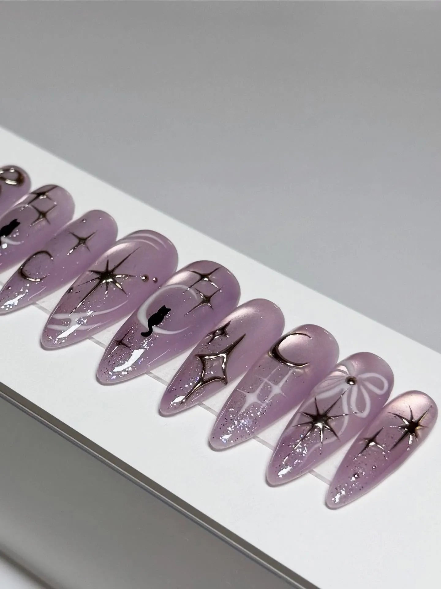 Handmade purple stiletto press-on nails with celestial cat, moon, star, and shimmer designs