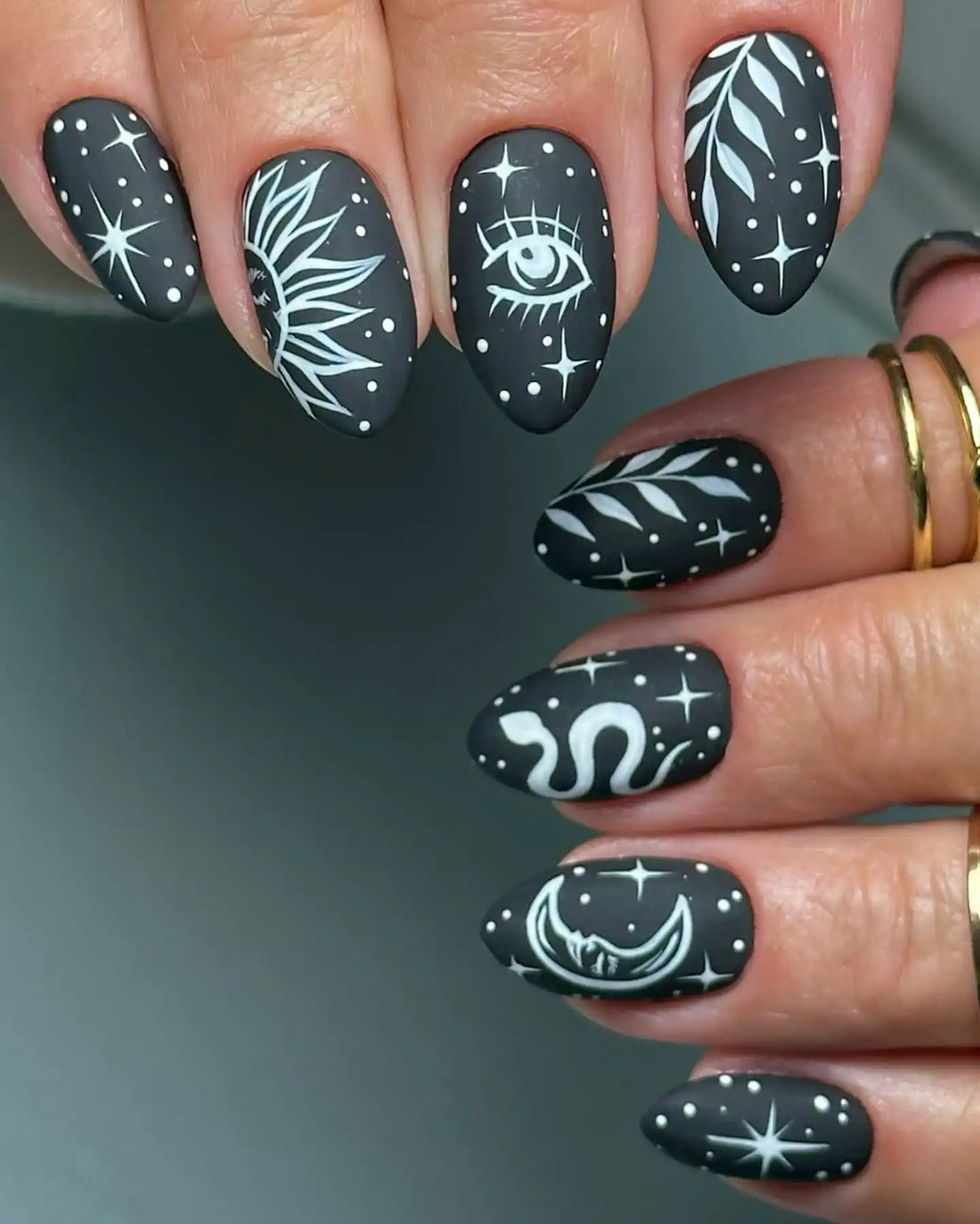 Handmade black matte press-on nails with celestial sun, moon, eye, snake and star designs