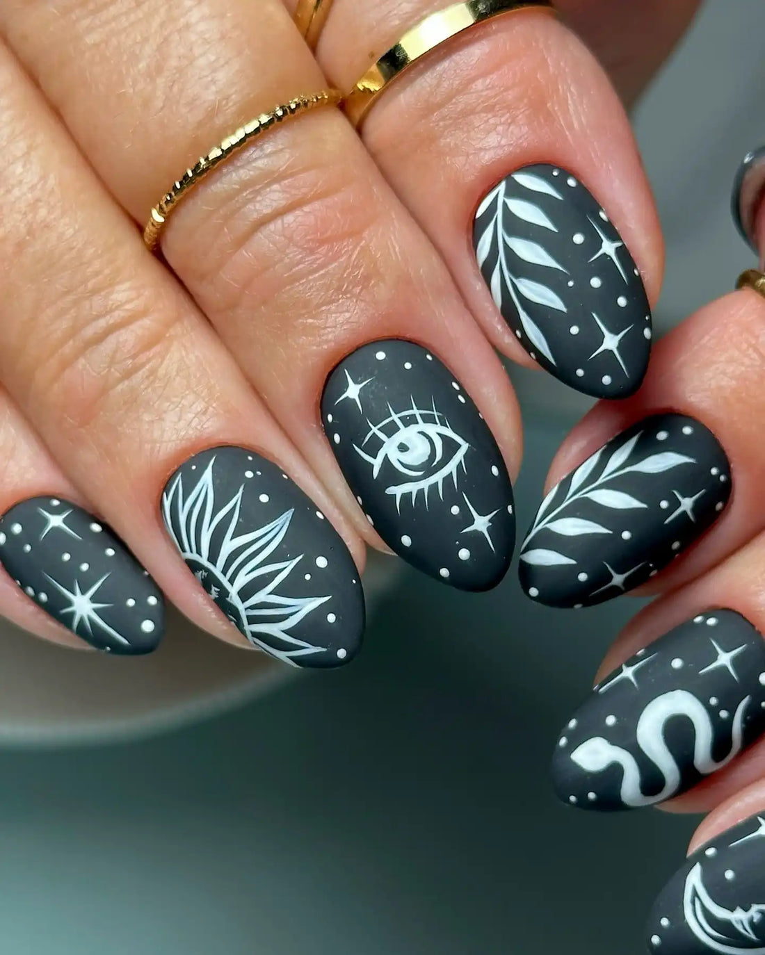Handmade black matte press-on nails with celestial sun, moon, eye, snake and star designs