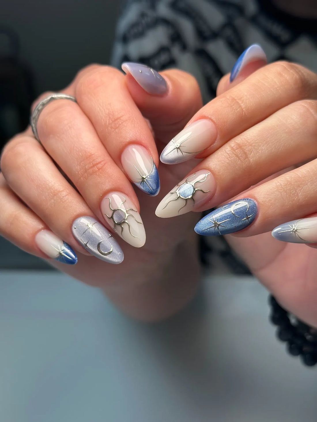 Handmade celestial press-on nails with sun, moon, and star designs in blue and nude shades