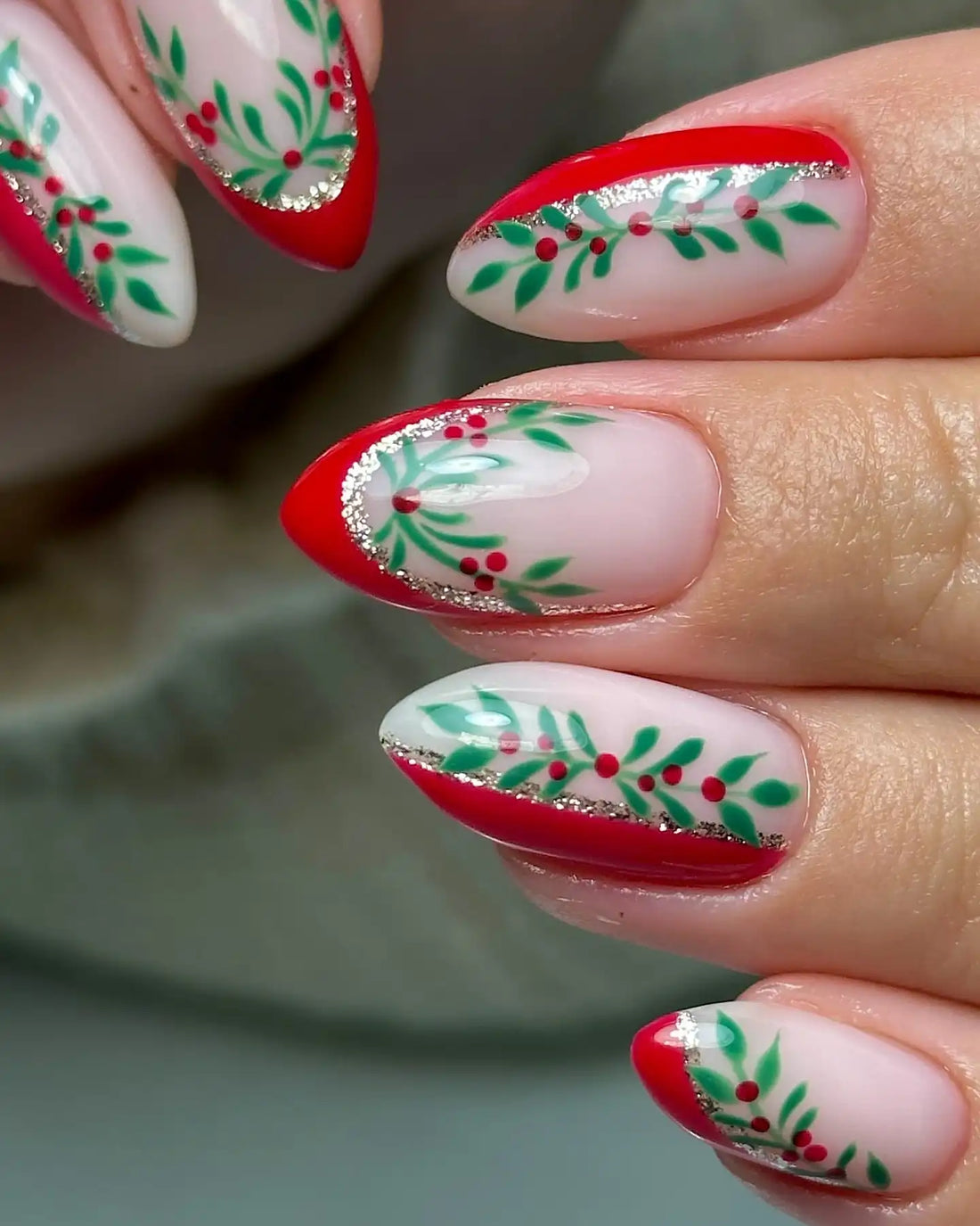 Handmade Christmas press-on nails with red tips, green holly leaves, and red berry designs.
