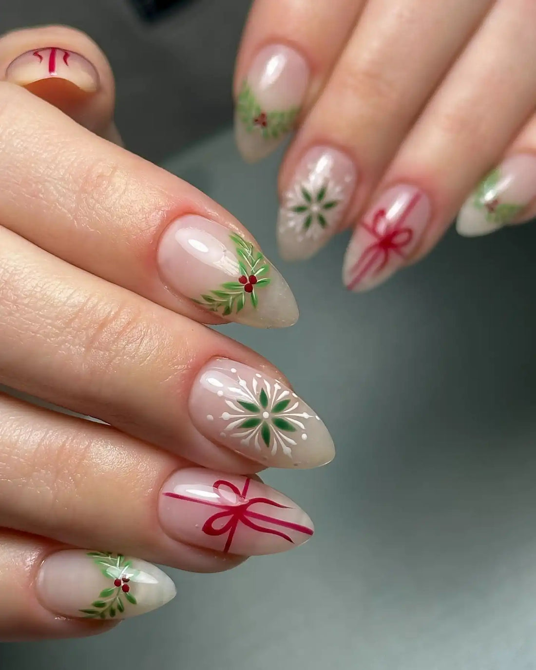 Handmade press-on nails with Christmas designs, holly berries, ribbon bows, and snowflake art