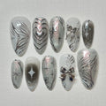 Handmade silver press-on nails with butterfly, heart, star, and abstract designs