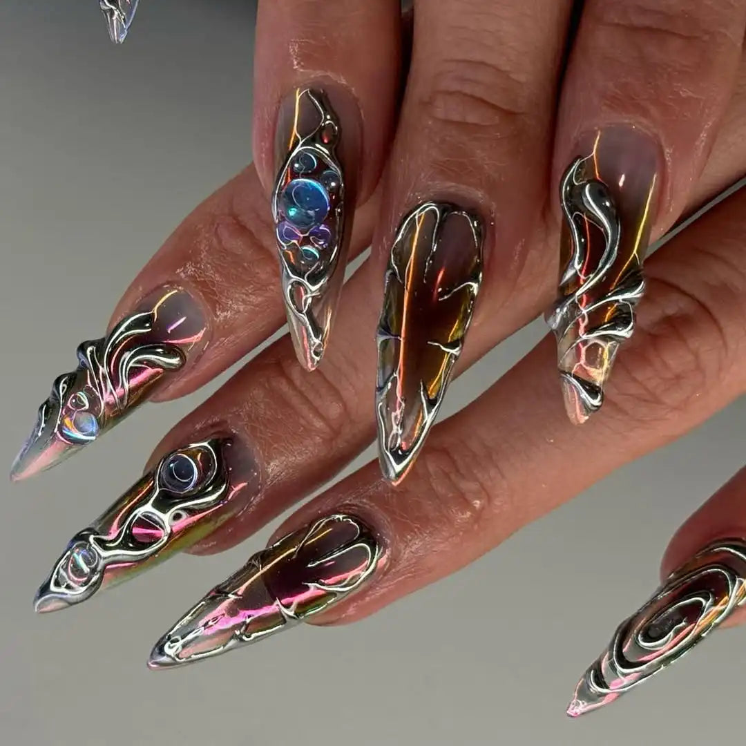 Hand with long handmade chrome silver press-on nails featuring sculpted 3D designs