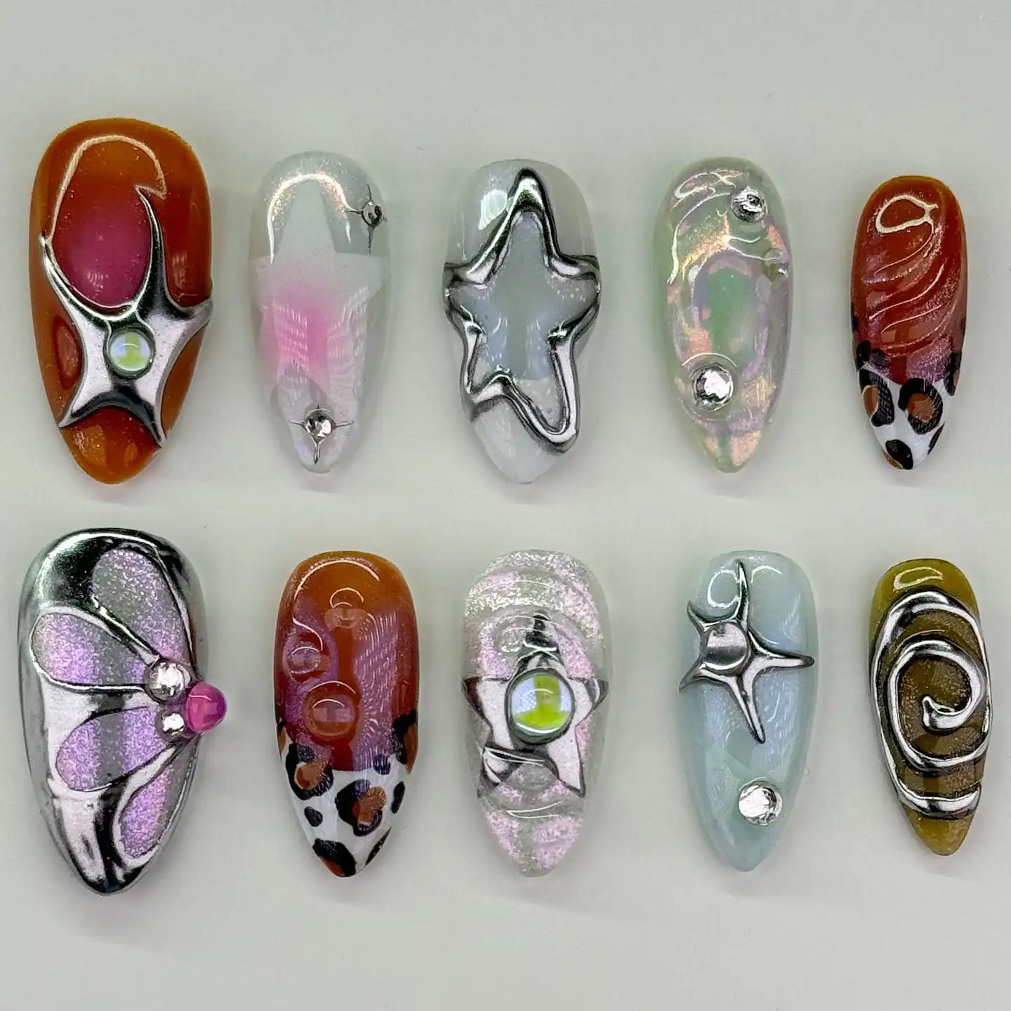 Handmade press-on nails with Y2K chrome stars, metallic swirls, and leopard print accents.