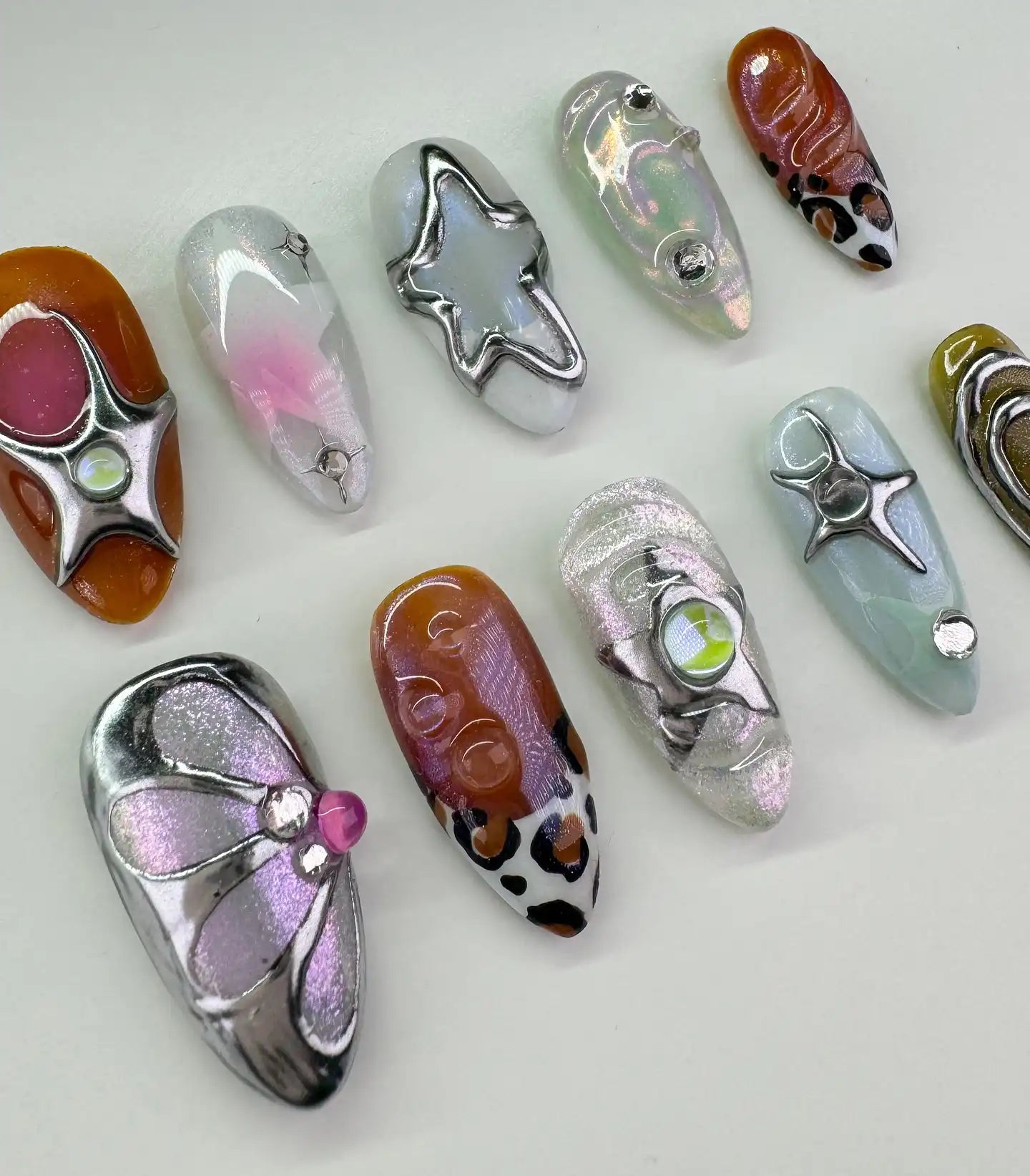 Handmade metallic press-on nails with chrome stars, swirls, and Y2K-inspired designs