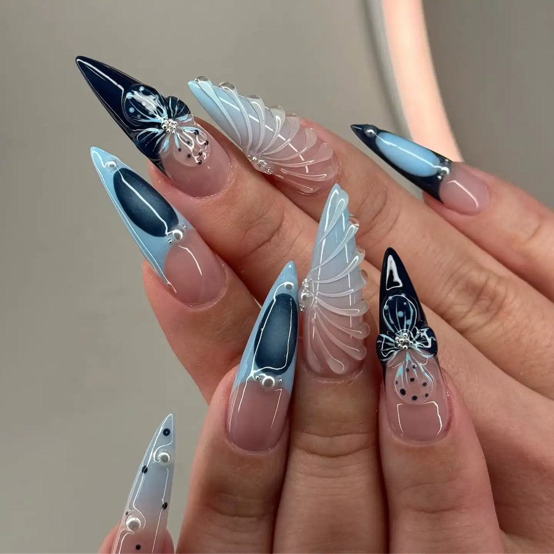 Handmade stiletto press-on nails with clear floral designs in black and light blue.