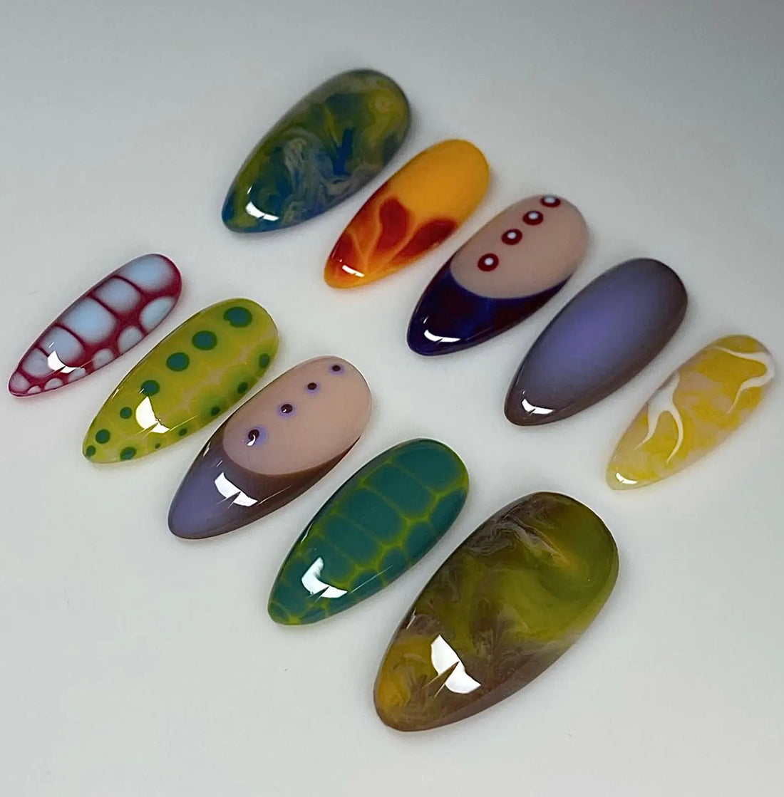 Handmade colorful graffiti press-on nails with abstract and geometric patterns on white background