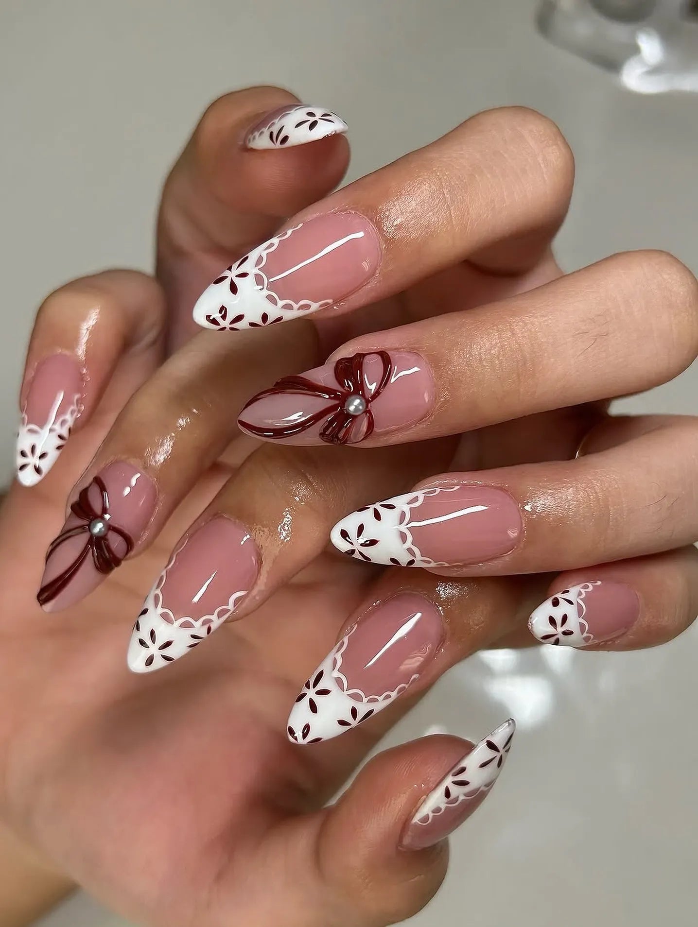 Handmade French tip press-on nails with white lace, floral patterns and 3D red bow accents.