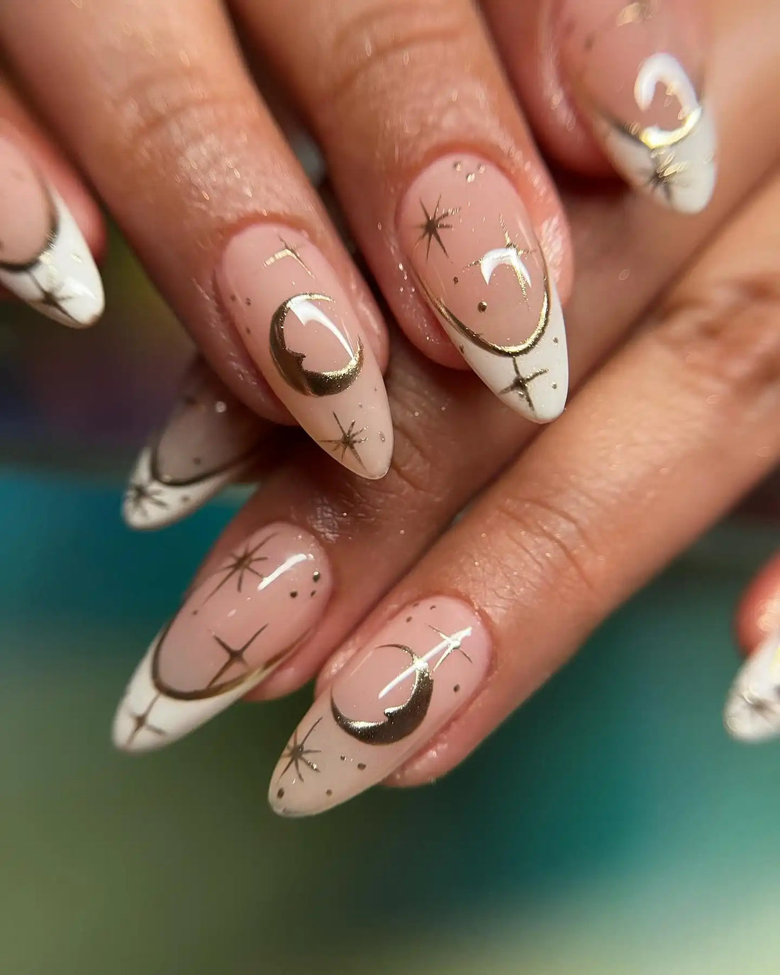 Handmade press-on nails with gold crescent moon and star designs on nude and white tips.