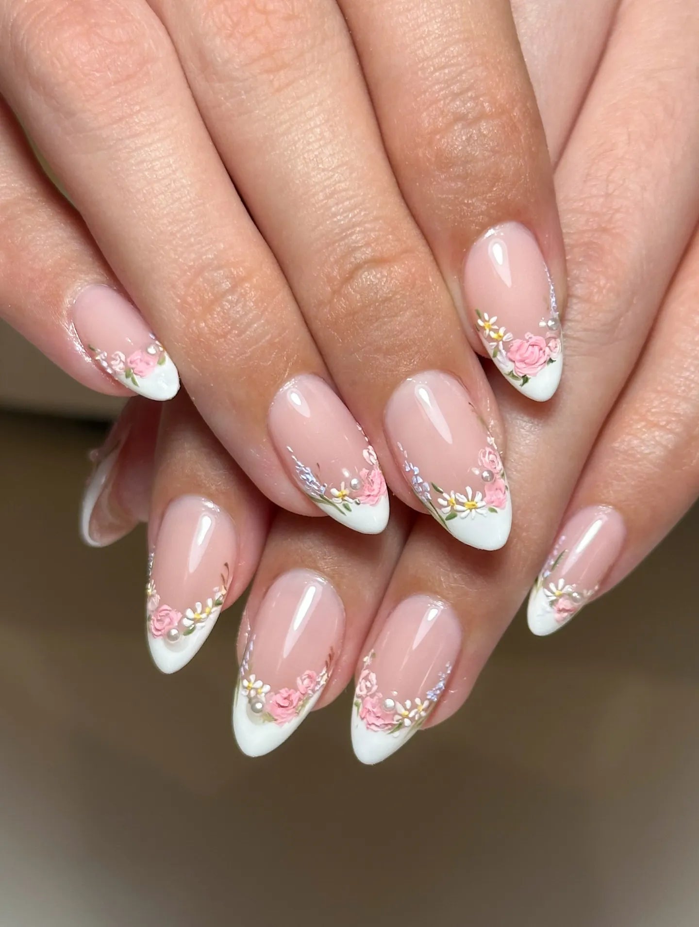 Handmade press-on nails with white French tips, pink floral designs, and pearl accents.