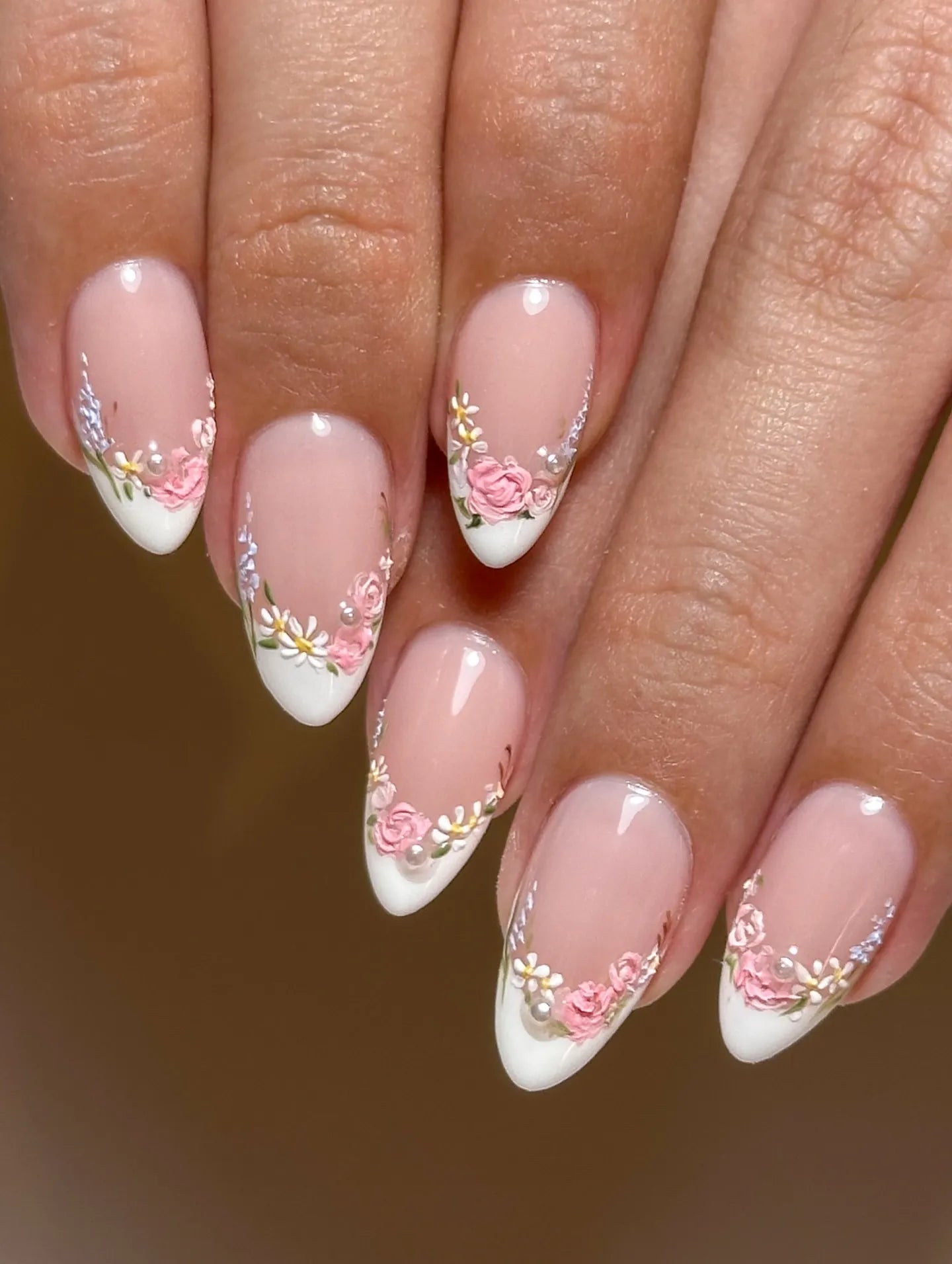 Handmade pink floral French tip press-on nails with pearl accents on natural hands