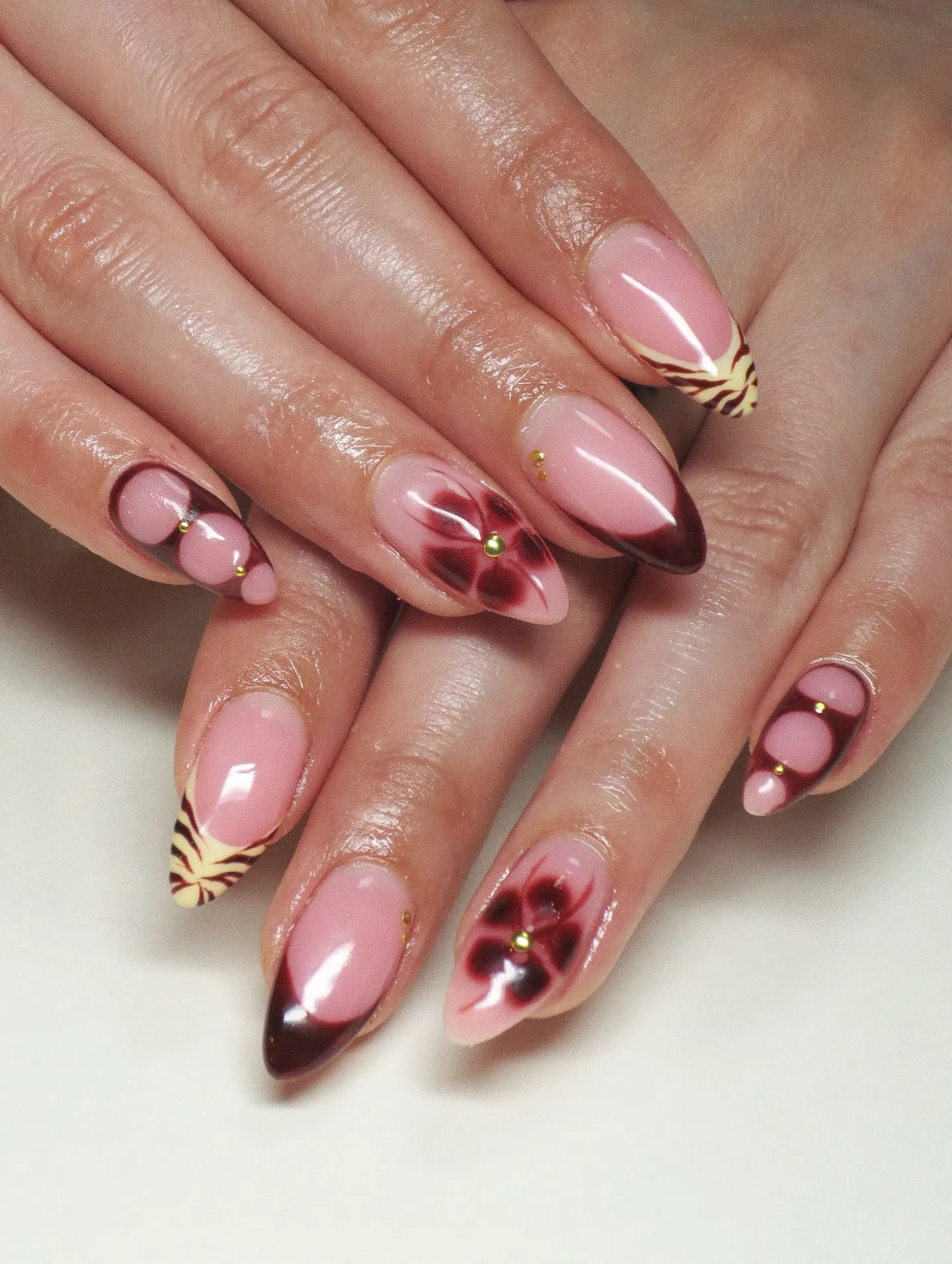 Handmade press-on nails with dark cherry French tips, floral and tiger print accents.