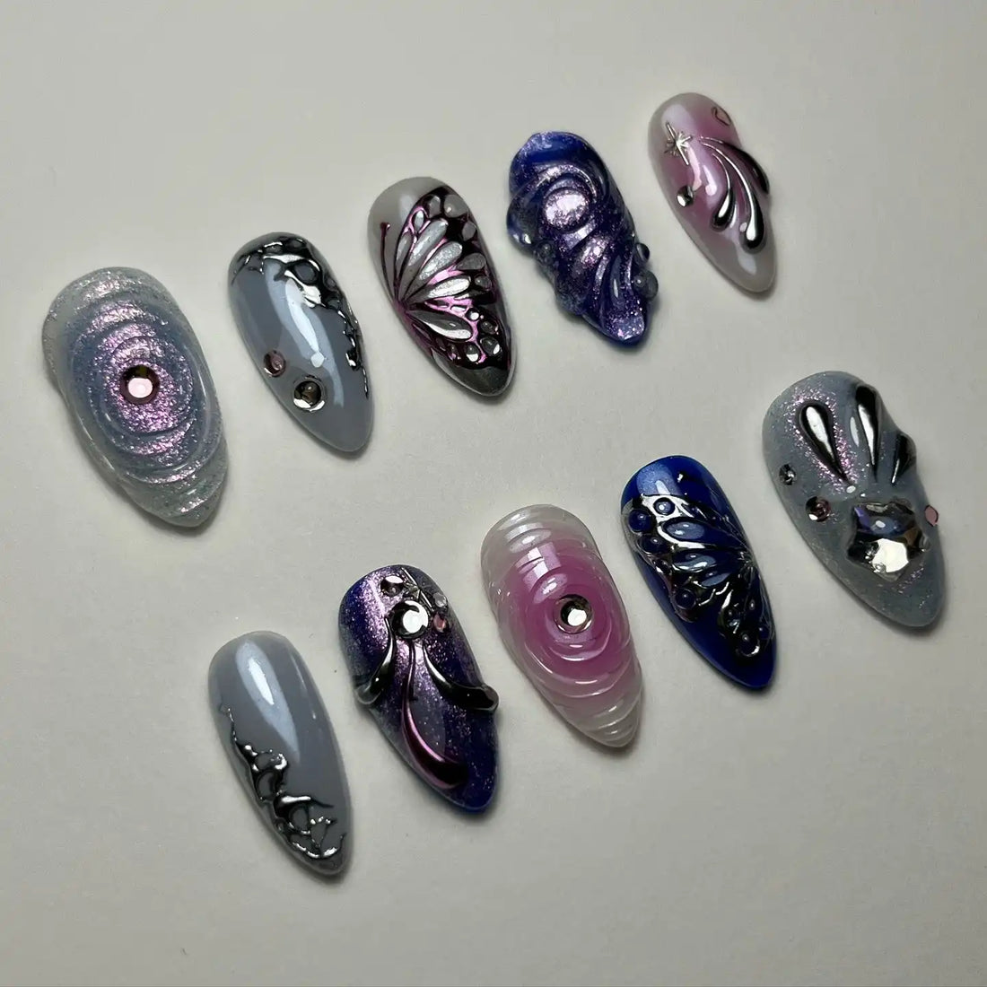 Handmade purple and silver press-on nails with chrome butterfly and rhinestone designs