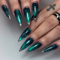 Hand with long stiletto press-on nails in deep teal nebula design with silver metallic edges