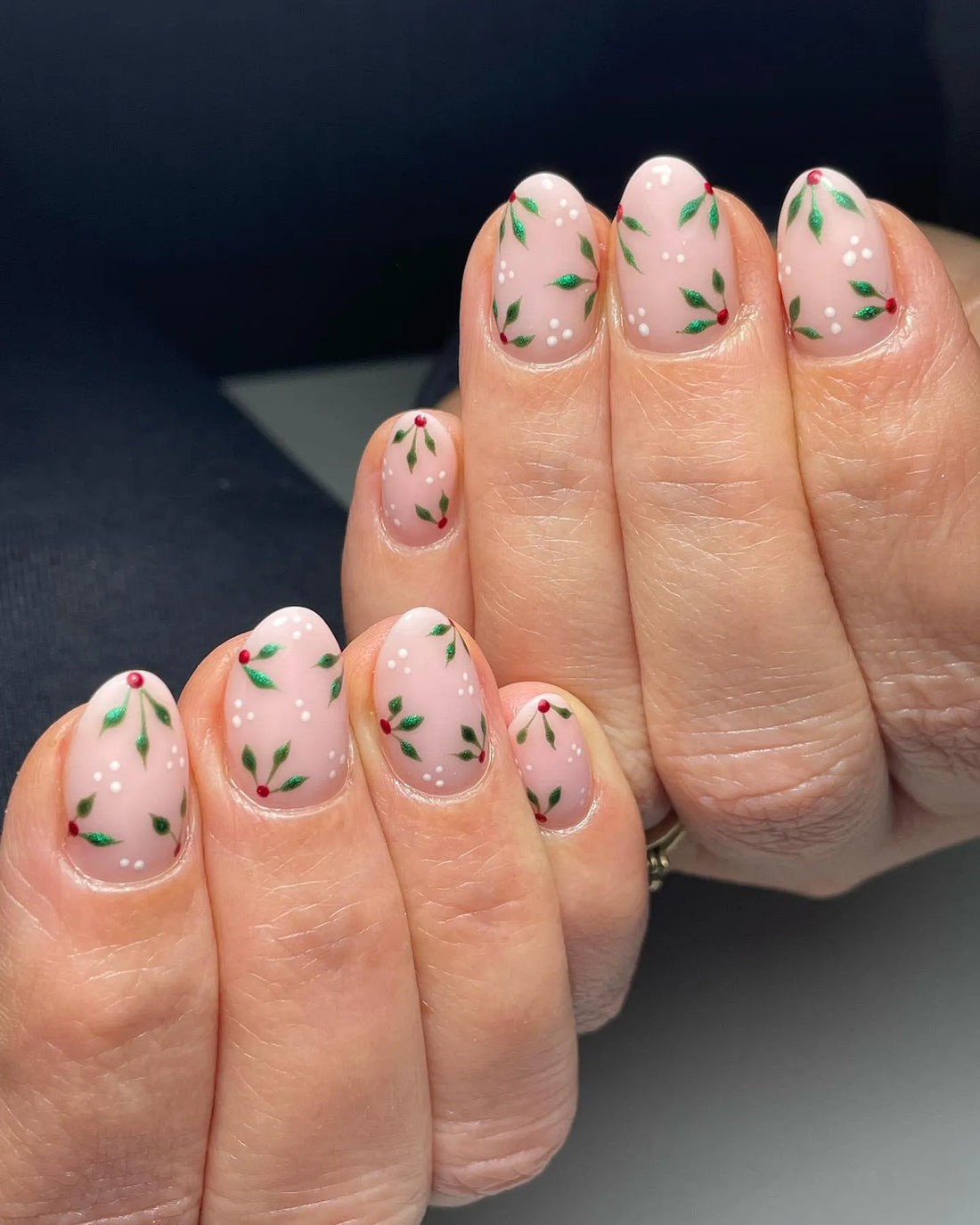 Handmade nude press-on nails with holly leaf, red berry, and white snow dot winter design