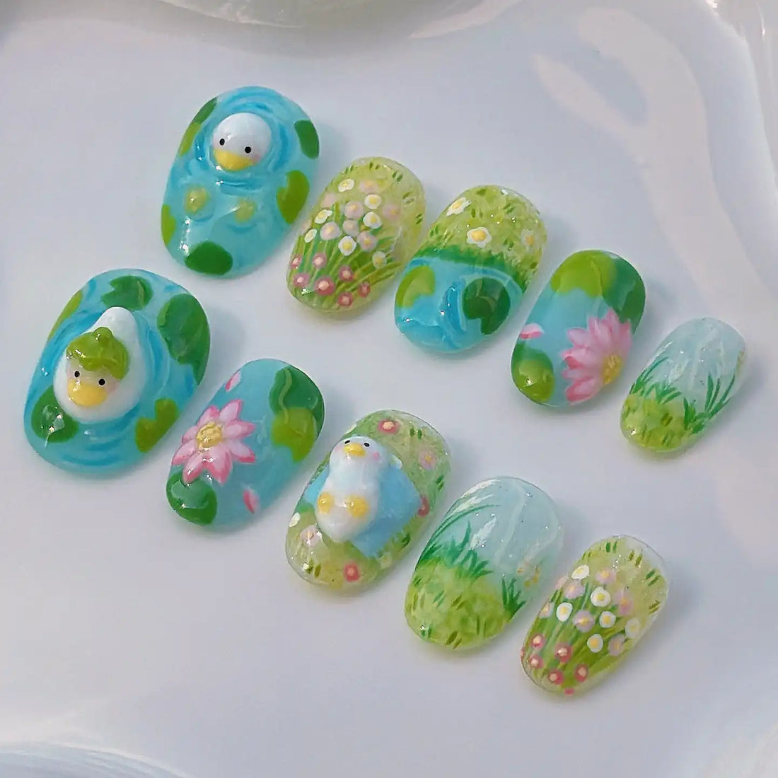 Handmade press-on nails with duck, flowers, and garden designs in green and blue tones