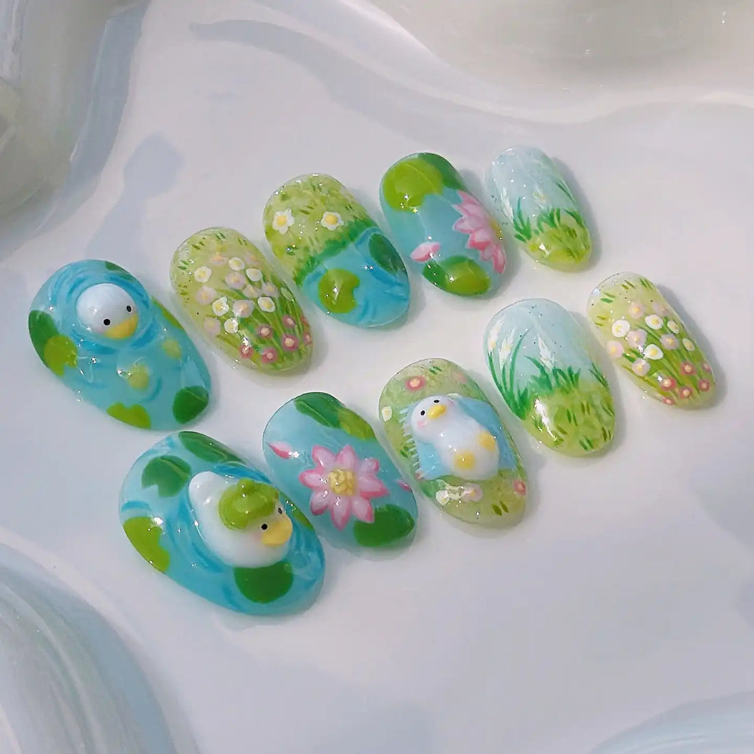 Handmade press-on nails with duck, flowers, and garden designs in green and blue tones