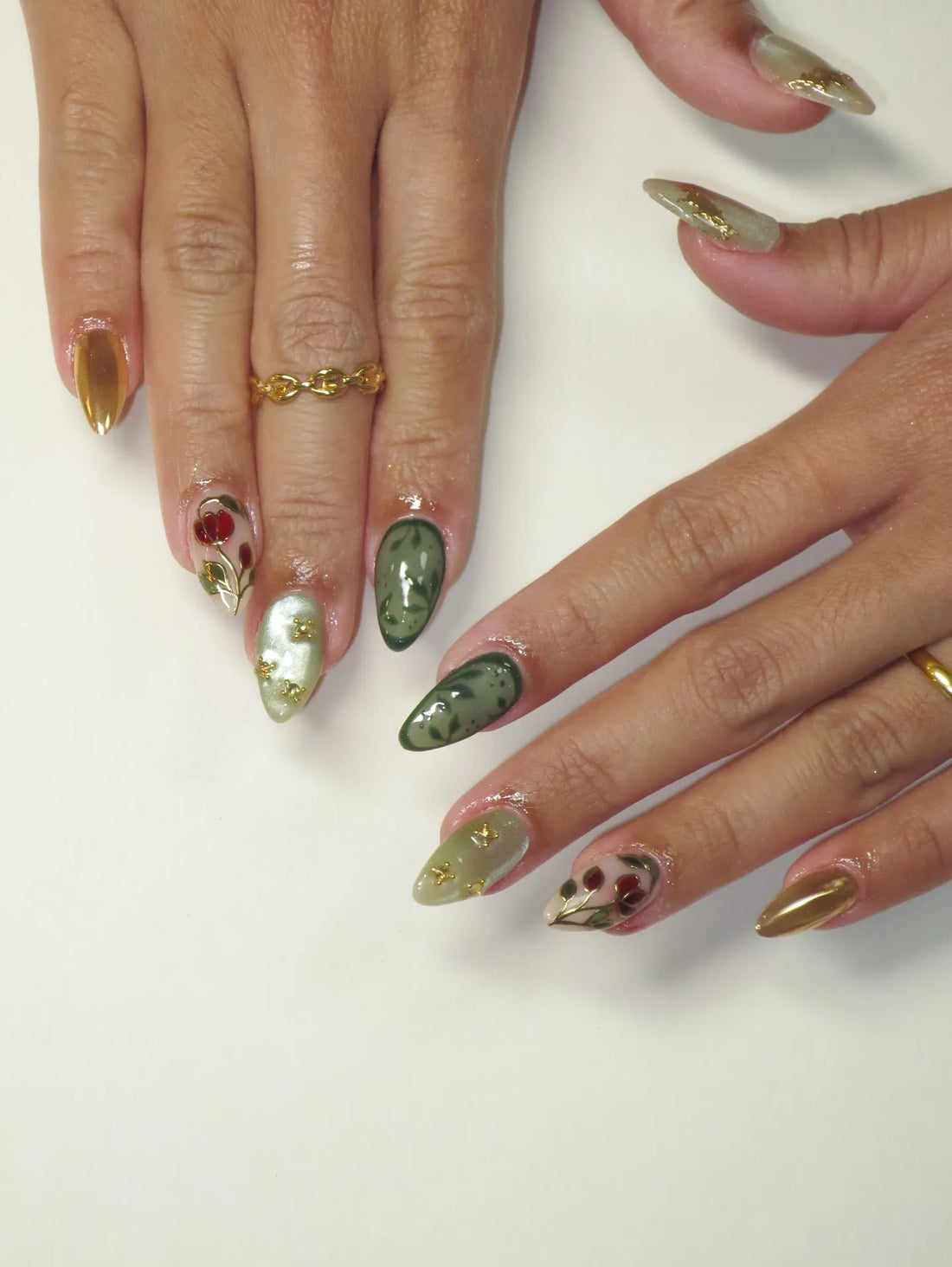Handmade green and gold press-on nails with rose and vine designs, cat eye shimmer finish