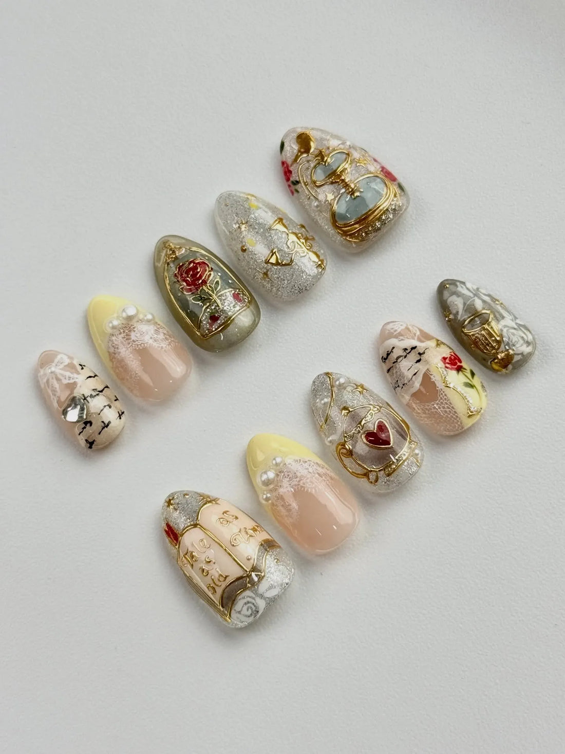 Handmade fairytale press-on nails with gold rose, book, chandelier, pearl, and floral accents.