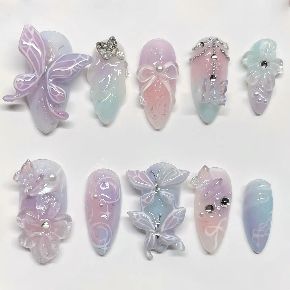 Handmade pastel fairycore press-on nails with butterfly, pearl, flower, and rhinestone designs.