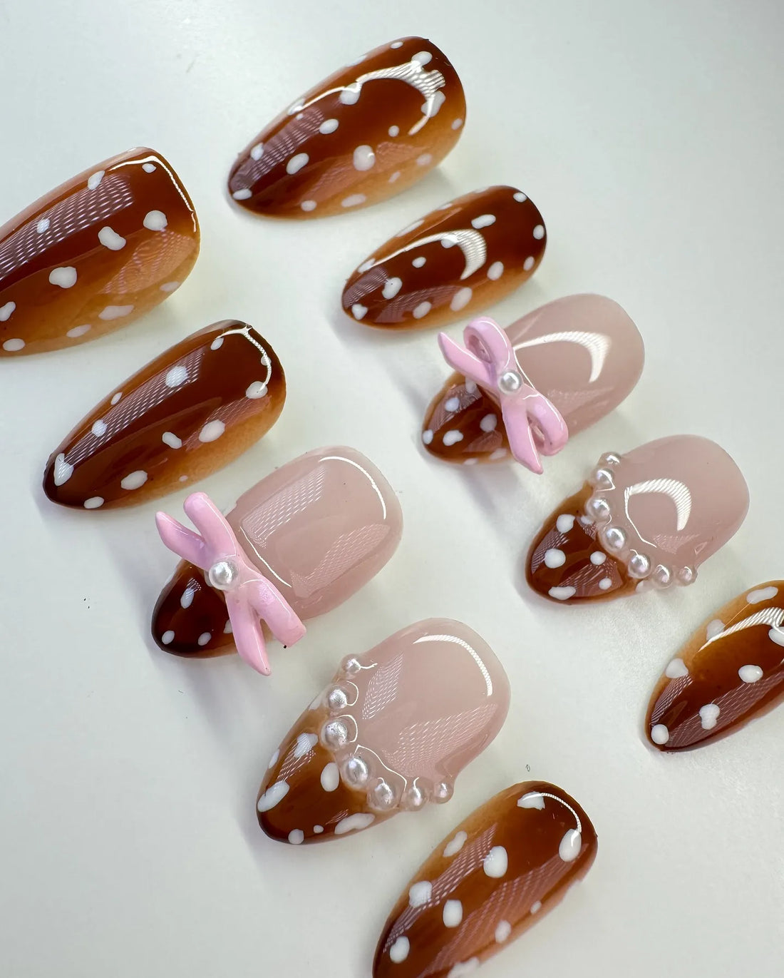 Handmade press-on nails with fawn print, pink bows, pearls, and white polka dots.
