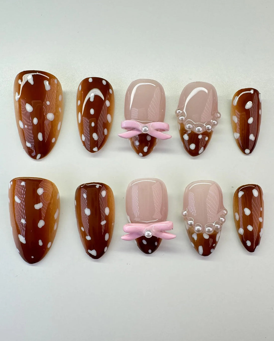 Handmade press-on nails with fawn print, pink bows, pearls, and white polka dots.