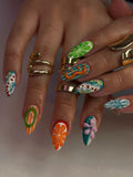 Hand with colorful handmade press-on nails featuring 3D abstract, flower, and swirl designs.