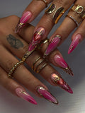 Hand with long hot pink ombre press-on nails, gold chrome accents, and sacred heart designs.