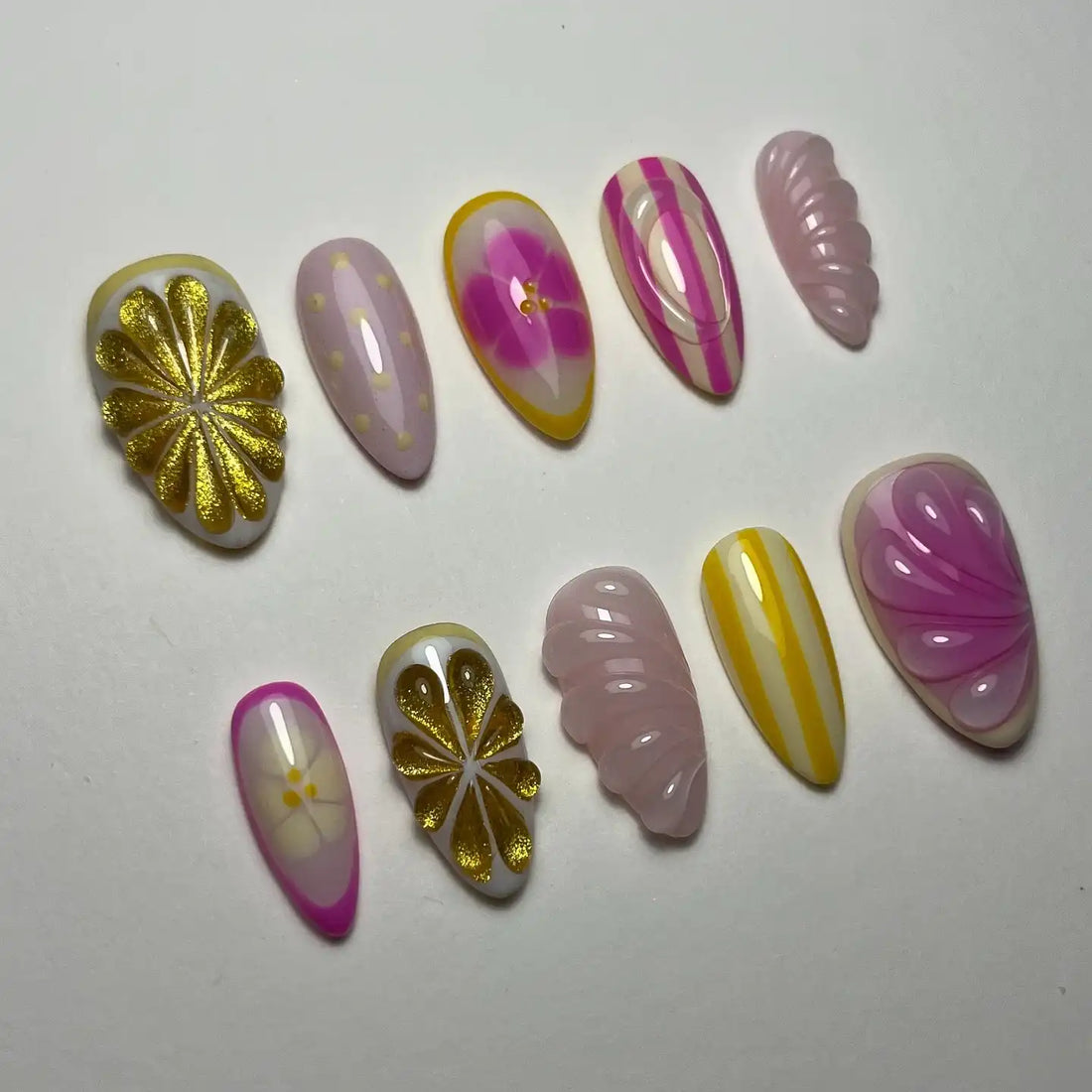 Handmade press-on nails with gold floral, pink stripe, and abstract summer designs.