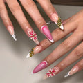Handmade gold floral French tip press-on nails with pink accents and 3D flower designs