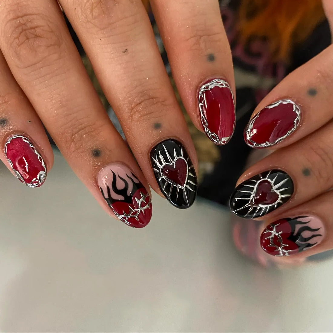Handmade gothic press-on nails with red heart, flame, and silver chrome accents.
