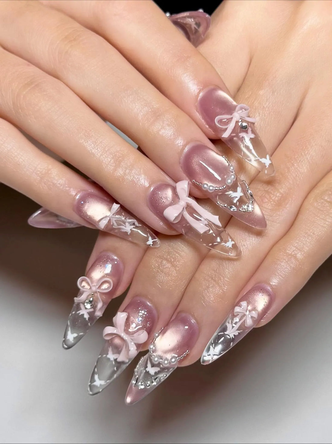 Handmade stiletto press-on nails with pink bows, pearls, stars, and celestial nail art.