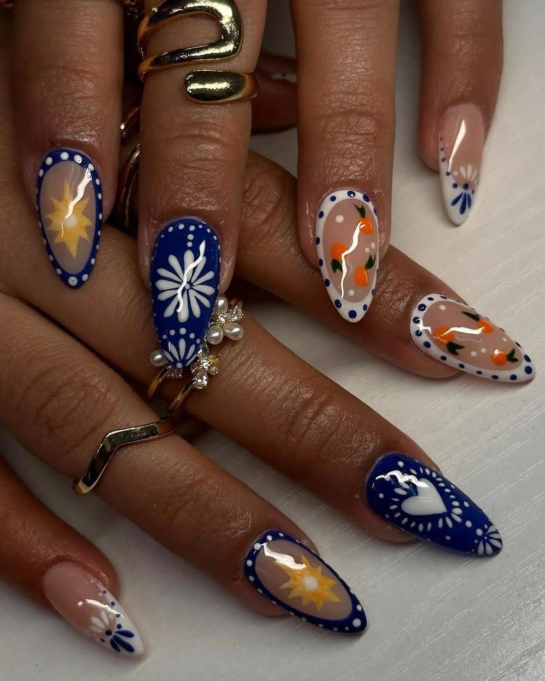 Handmade glossy press-on nails with blue, citrus, floral, heart, and sun designs.