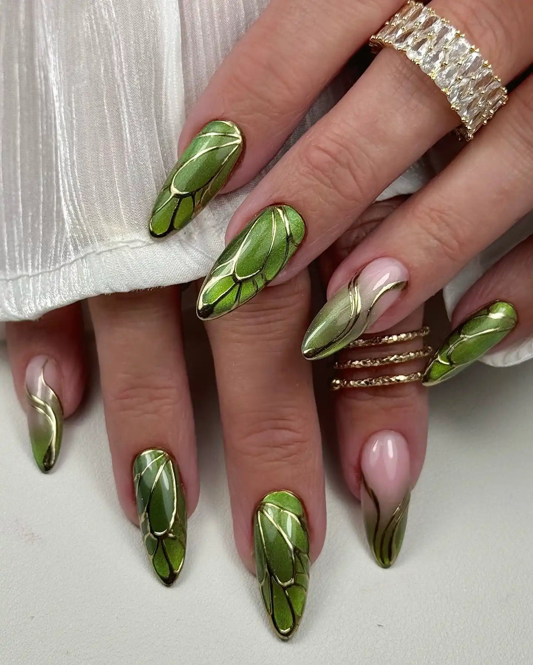 Handmade green leaf art press-on nails with gold chrome accents, almond shape