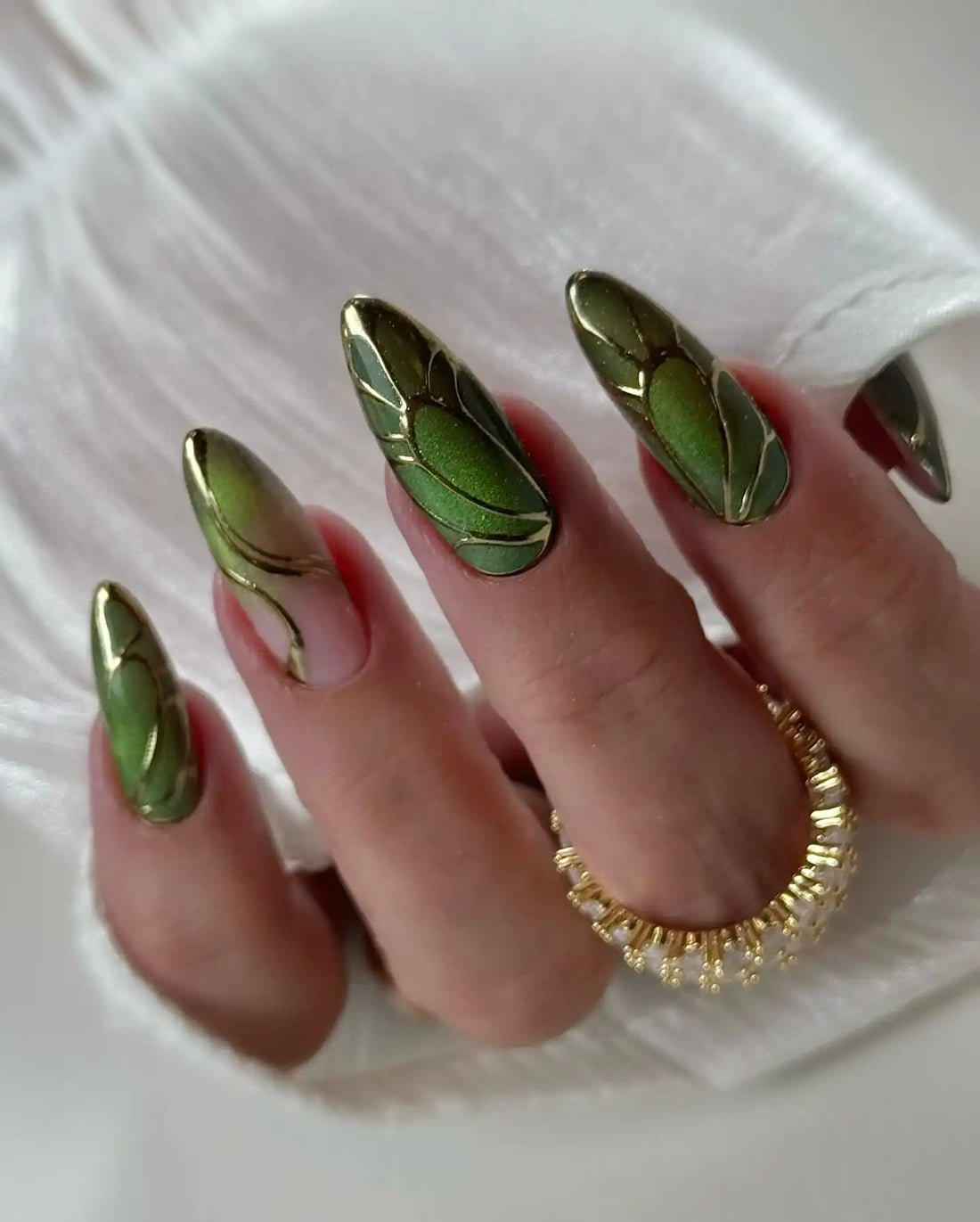 Handmade green leaf art press-on nails with gold chrome accents, almond shape