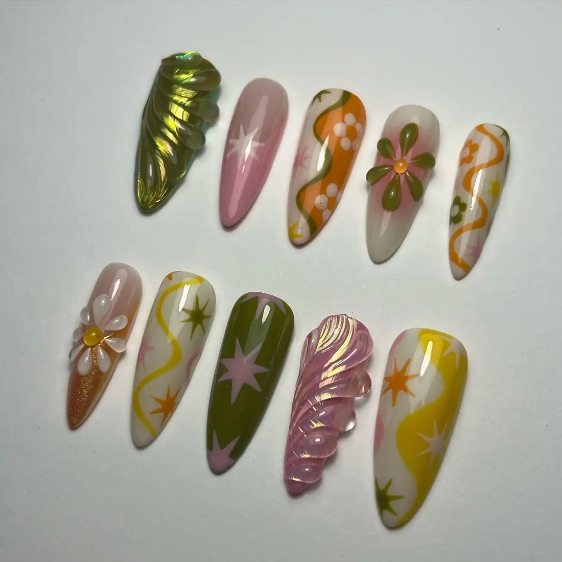 Handmade press-on nails with groovy retro designs in pink, orange, green, and floral patterns.