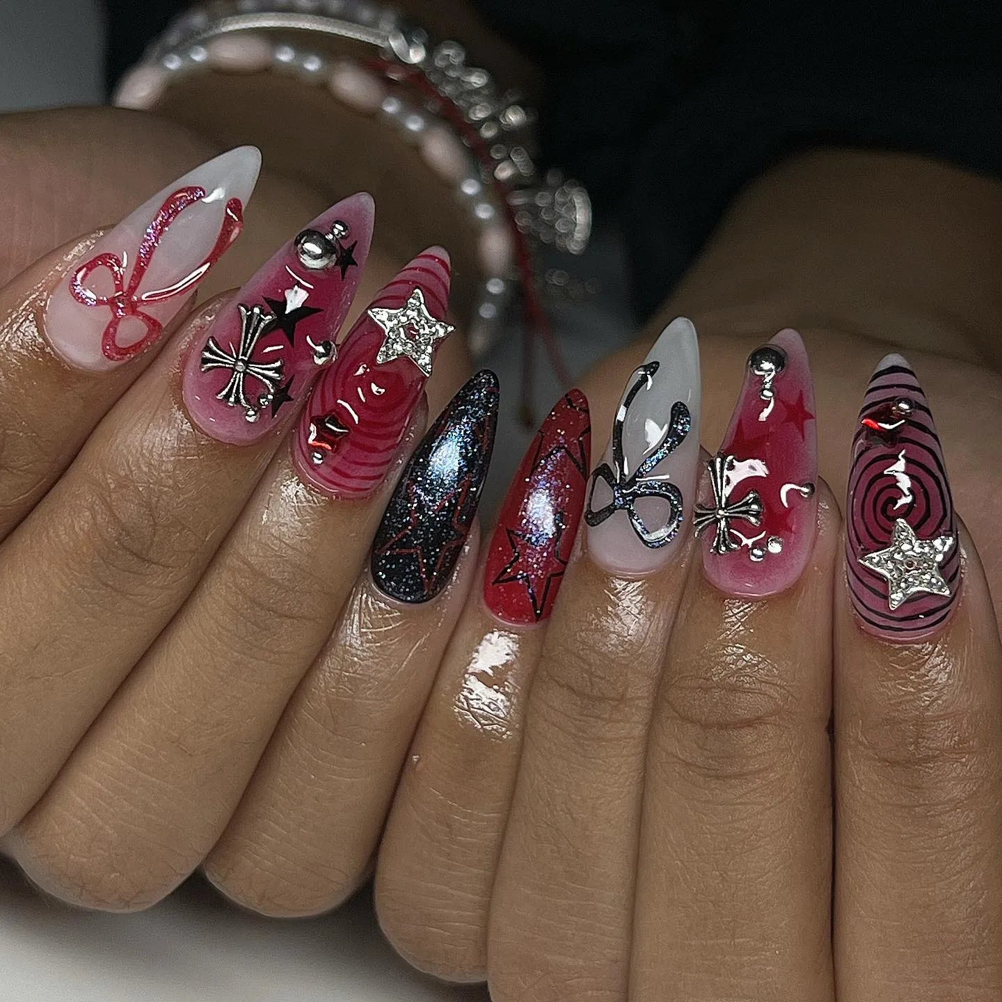 Handmade press-on nails with black, red, and chrome grunge designs, crosses, stars, and ribbons.