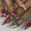 Handmade grunge goth red and black press-on nails with chrome cross, star, and ribbon designs.