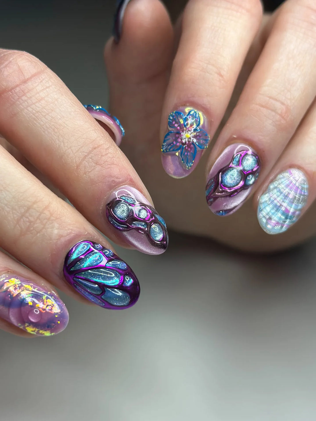 Handmade iridescent fantasy press-on nails with 3D butterfly, flower, and shell designs