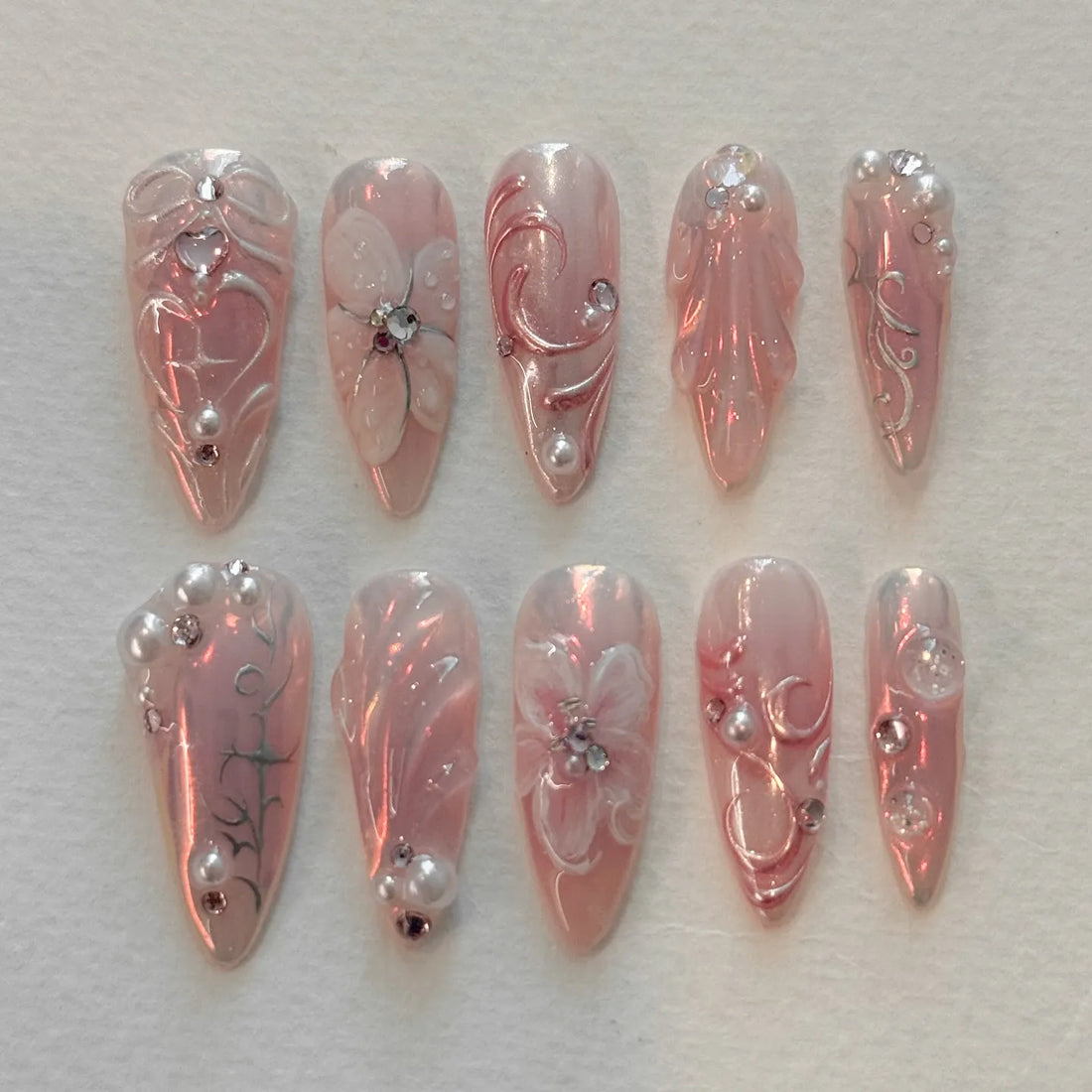 Handmade iridescent pink press-on nails with pearl, rhinestone, floral, and vine designs